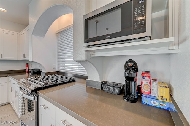 kitchen featuring appliances with stainless steel finishes, white cabinets, and light tile patterned floors