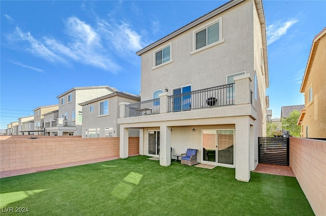 rear view of house with a lawn and a balcony