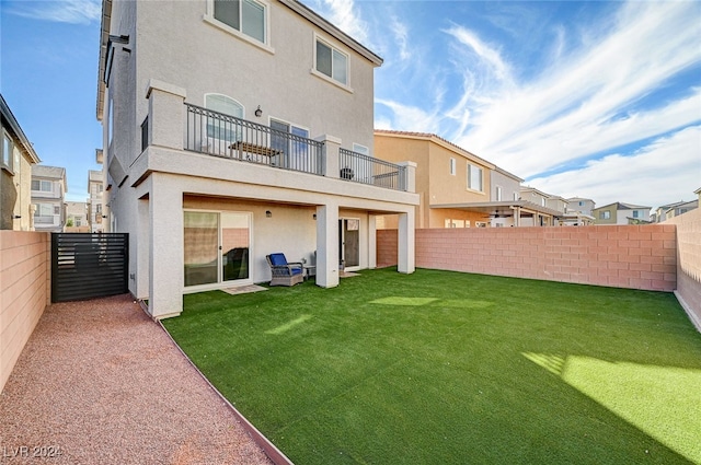 rear view of house featuring a yard and a balcony