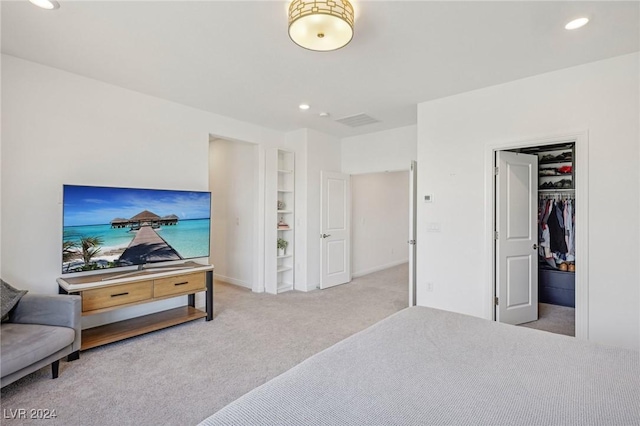 bedroom with a walk in closet and light carpet