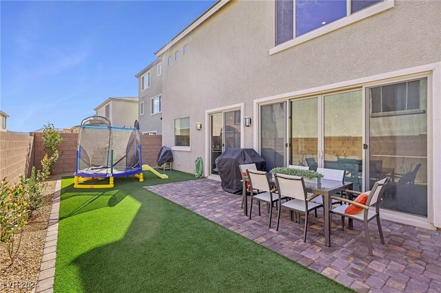 back of house with a yard, a patio area, and a trampoline