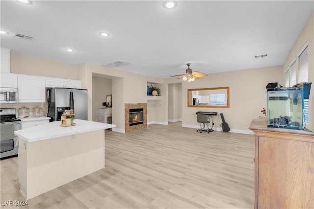 kitchen with white cabinetry, a center island, light hardwood / wood-style flooring, ceiling fan, and stainless steel appliances