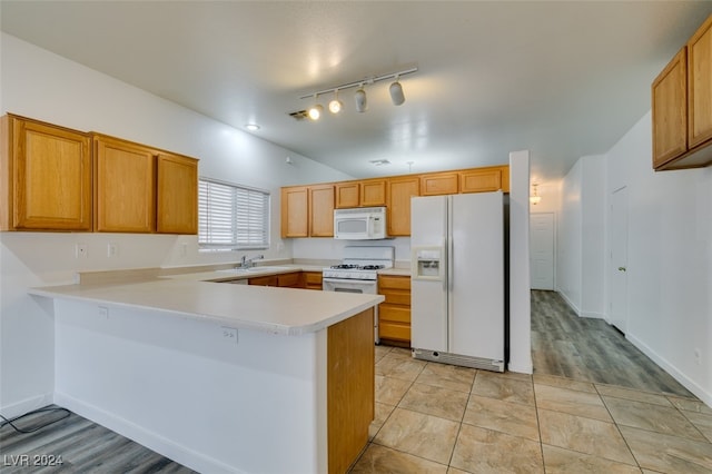 kitchen featuring white appliances, sink, kitchen peninsula, light hardwood / wood-style floors, and rail lighting