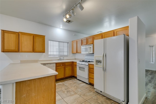 kitchen featuring kitchen peninsula, lofted ceiling, track lighting, sink, and white appliances