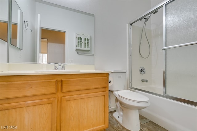 full bathroom with vanity, toilet, wood-type flooring, and shower / bath combination with glass door