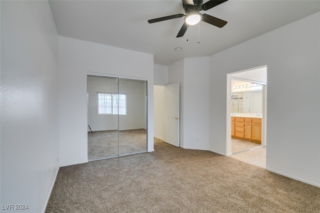 unfurnished bedroom with ensuite bath, light carpet, a closet, and ceiling fan