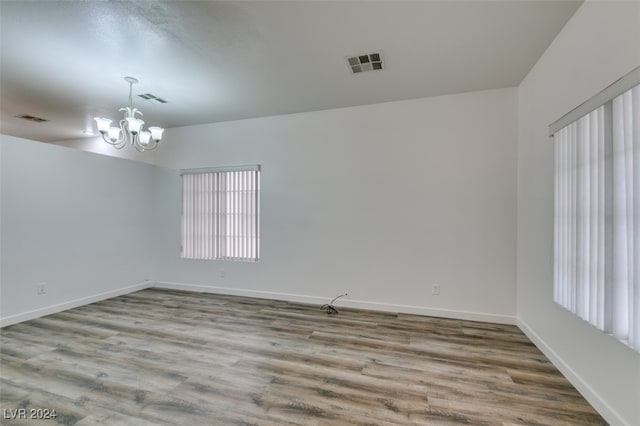 spare room with light hardwood / wood-style flooring and an inviting chandelier