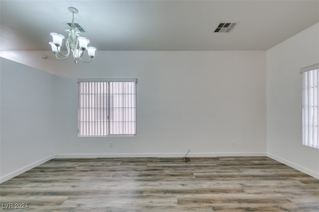 spare room with an inviting chandelier and light wood-type flooring