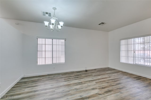 spare room featuring an inviting chandelier and hardwood / wood-style flooring