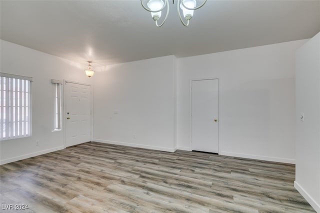 empty room with a notable chandelier and light wood-type flooring