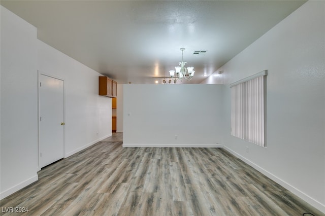 empty room with light hardwood / wood-style flooring and a chandelier