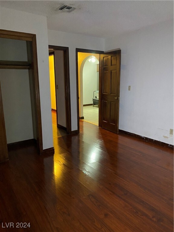 unfurnished bedroom featuring a textured ceiling, dark hardwood / wood-style floors, and a closet