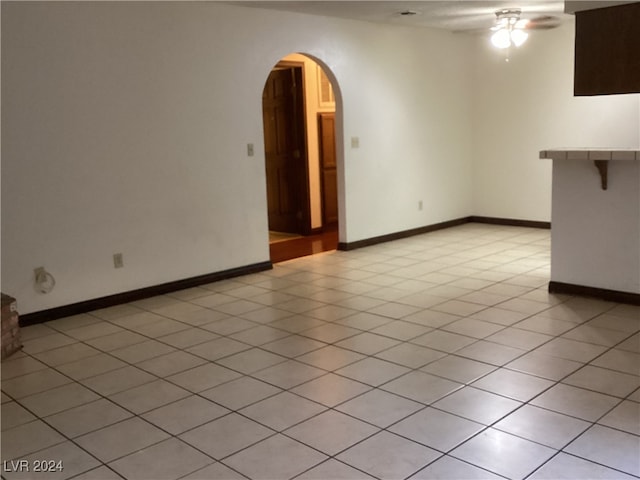 tiled empty room featuring ceiling fan