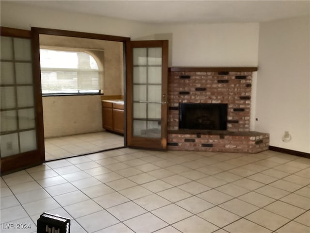 unfurnished living room with light tile patterned floors and a brick fireplace