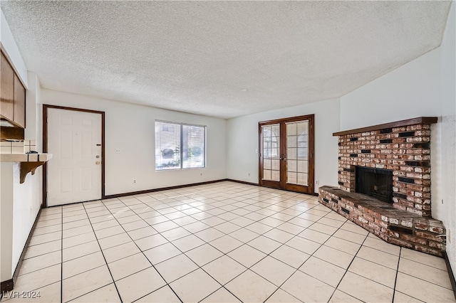 unfurnished living room with french doors, a brick fireplace, a textured ceiling, and light tile patterned floors