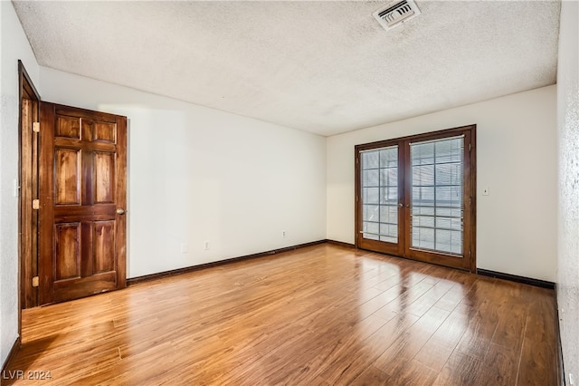 spare room with french doors, a textured ceiling, and light hardwood / wood-style flooring