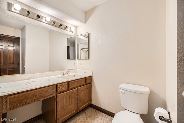 bathroom with toilet, vanity, and tile patterned floors