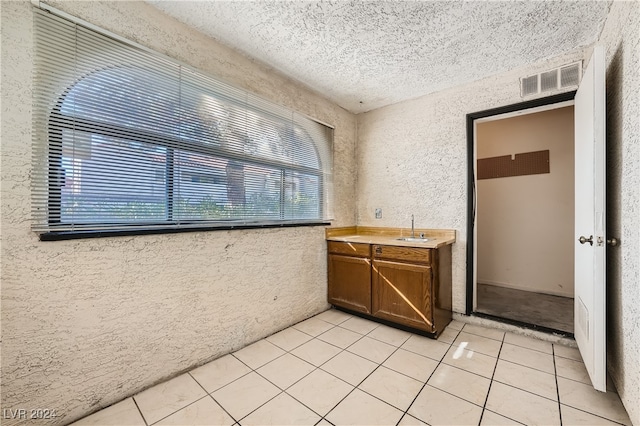 kitchen featuring sink, a textured ceiling, and light tile patterned floors