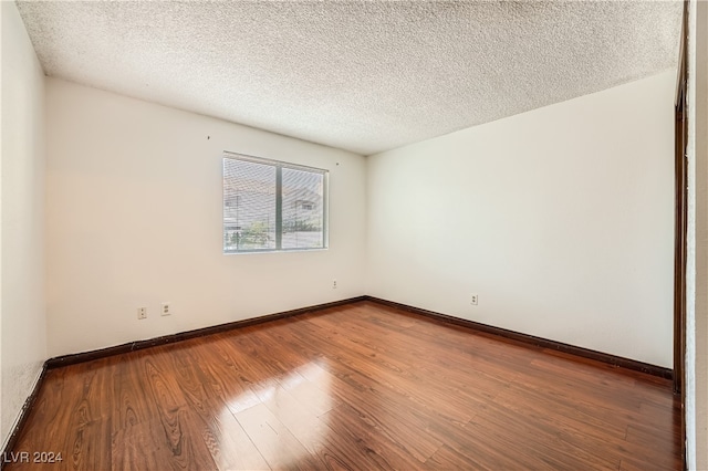 spare room with a textured ceiling and hardwood / wood-style floors