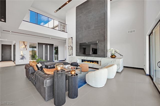 tiled living room with a towering ceiling and a premium fireplace