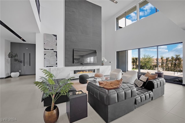 tiled living room featuring a premium fireplace and a towering ceiling