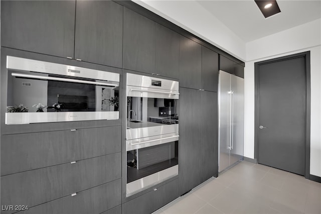 kitchen featuring stainless steel double oven and light tile patterned flooring