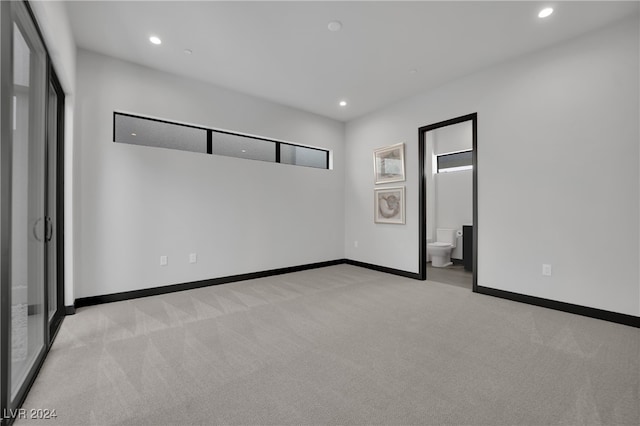 unfurnished bedroom with light colored carpet and connected bathroom