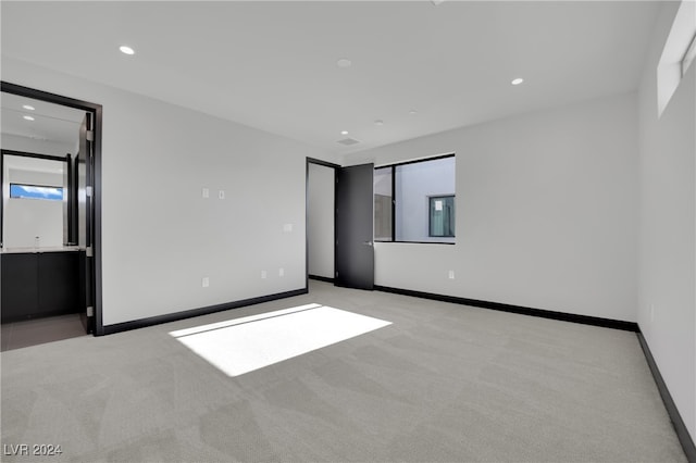 unfurnished bedroom featuring light colored carpet and ensuite bathroom