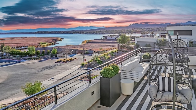 balcony at dusk featuring a water and mountain view