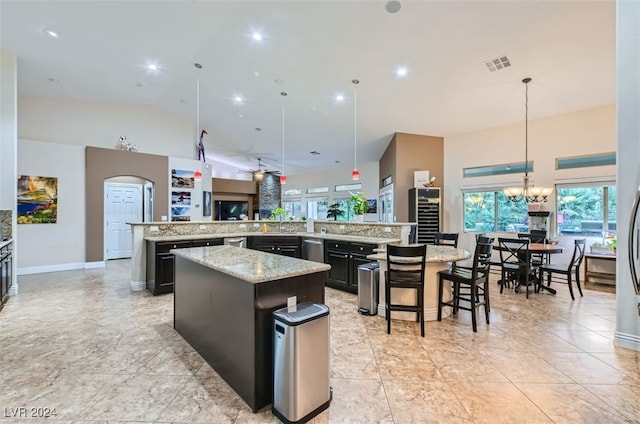 kitchen with pendant lighting, light stone countertops, a breakfast bar area, kitchen peninsula, and a spacious island