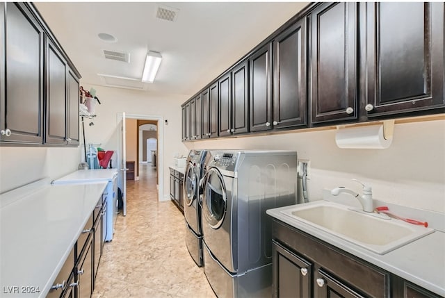 laundry area featuring washing machine and dryer, cabinets, and sink