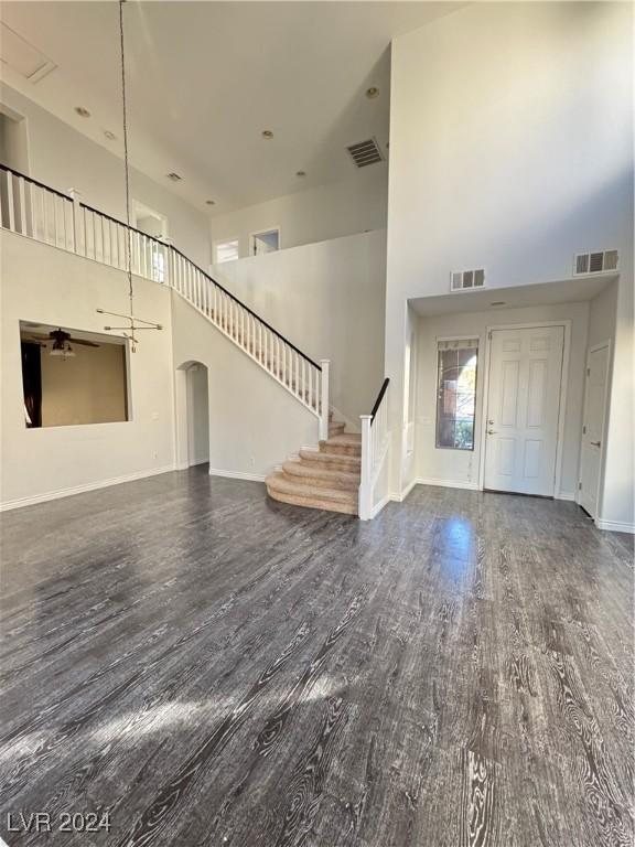 foyer entrance featuring a towering ceiling, ceiling fan, and dark wood-type flooring