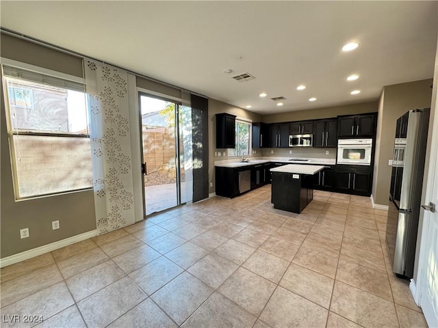 kitchen featuring a center island, light tile patterned floors, stainless steel appliances, and sink