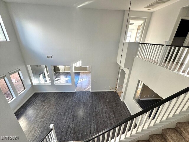 unfurnished living room featuring dark hardwood / wood-style floors, ceiling fan, and a towering ceiling