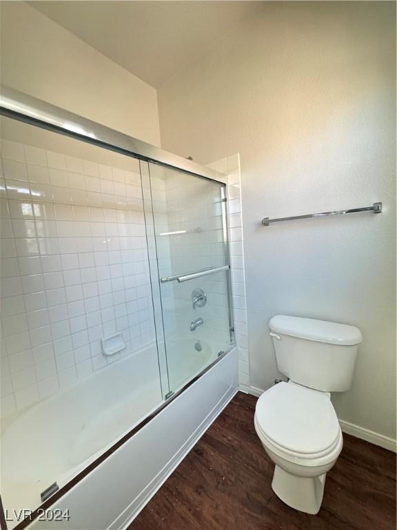 bathroom with hardwood / wood-style flooring, toilet, and enclosed tub / shower combo