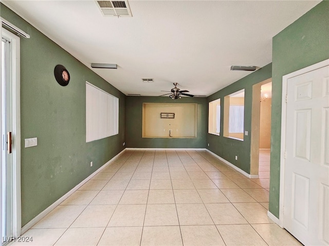 empty room featuring a wealth of natural light, light tile patterned floors, and ceiling fan