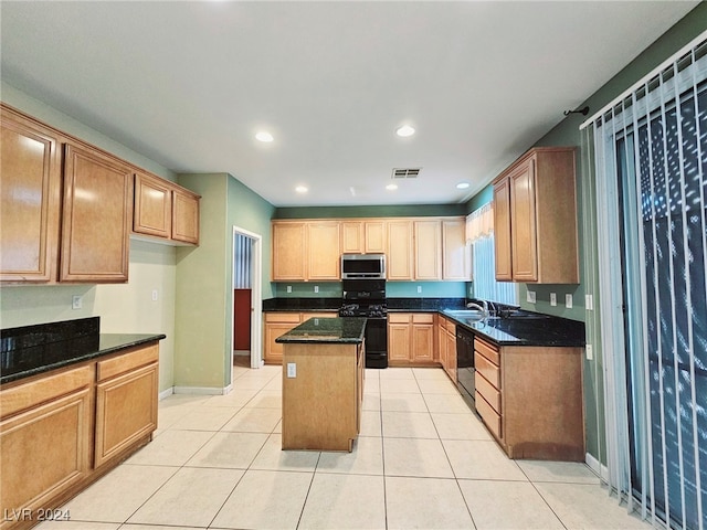 kitchen with dark stone counters, light tile patterned flooring, black appliances, and a kitchen island