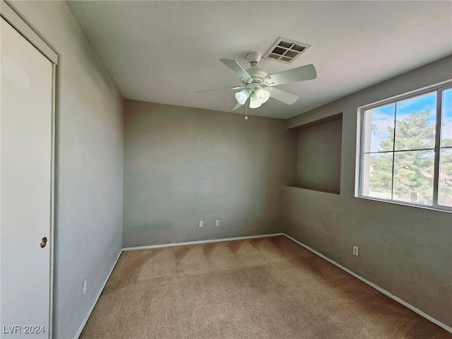 unfurnished room featuring a textured ceiling, light carpet, and ceiling fan