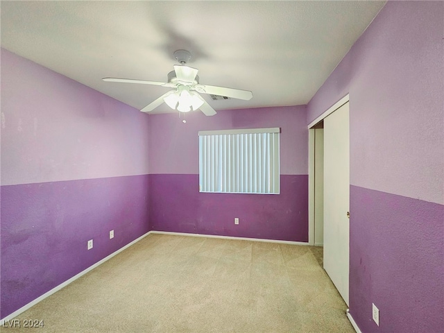 unfurnished bedroom with ceiling fan, light carpet, and a closet