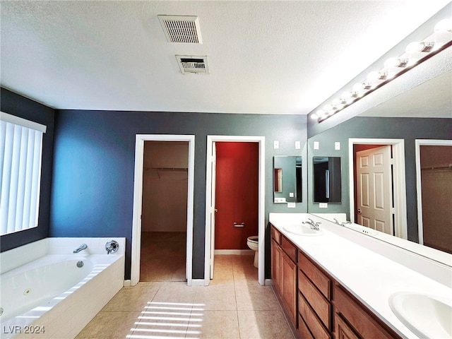 bathroom featuring tile patterned flooring, a relaxing tiled tub, a textured ceiling, vanity, and toilet