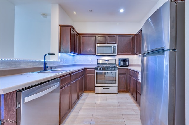 kitchen with backsplash, kitchen peninsula, sink, and appliances with stainless steel finishes