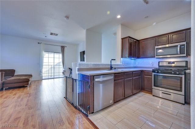 kitchen featuring kitchen peninsula, appliances with stainless steel finishes, light wood-type flooring, and sink