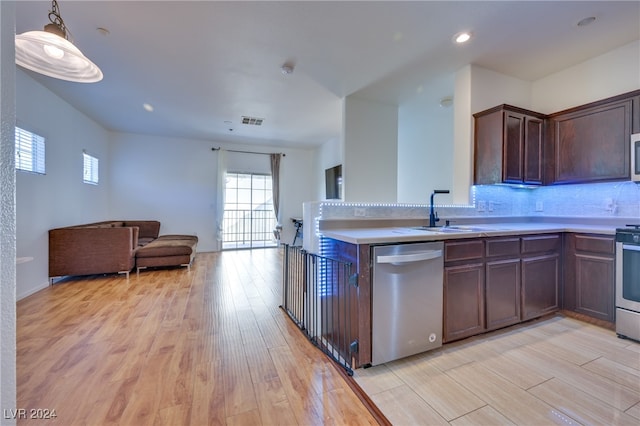 kitchen featuring decorative backsplash, light wood-type flooring, stainless steel appliances, sink, and decorative light fixtures