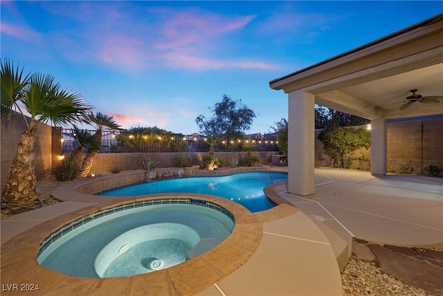 pool at dusk featuring ceiling fan, an in ground hot tub, and a patio area