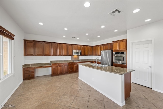 kitchen featuring stainless steel appliances, light tile patterned floors, sink, and a kitchen island with sink