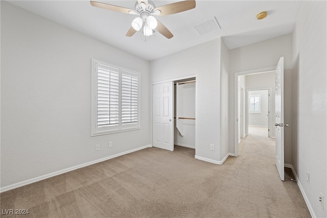 unfurnished bedroom featuring ceiling fan, light carpet, and a closet