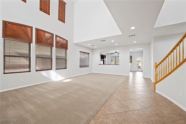 unfurnished living room with a high ceiling, light tile patterned floors, and ceiling fan