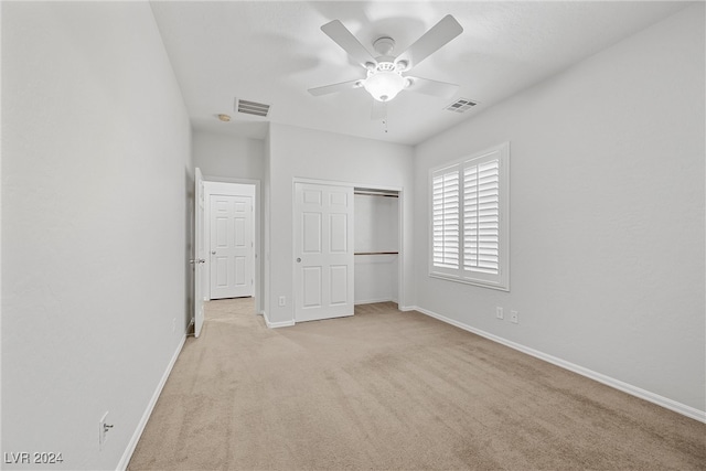 unfurnished bedroom featuring ceiling fan, light carpet, and a closet