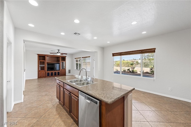 kitchen with stainless steel dishwasher, light tile patterned flooring, sink, and a kitchen island with sink