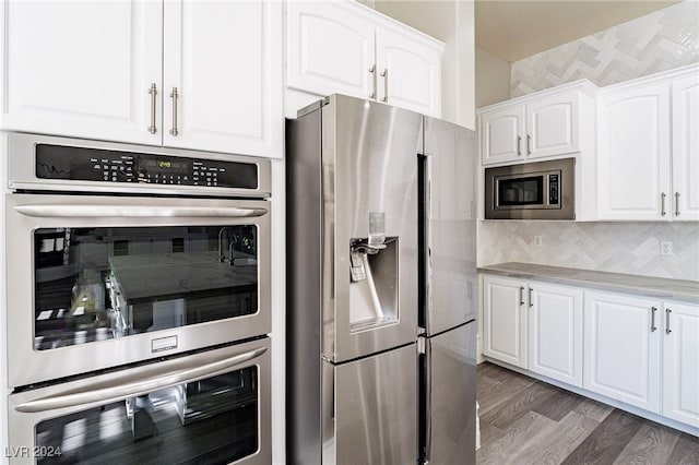 kitchen featuring white cabinets, decorative backsplash, appliances with stainless steel finishes, and dark hardwood / wood-style flooring